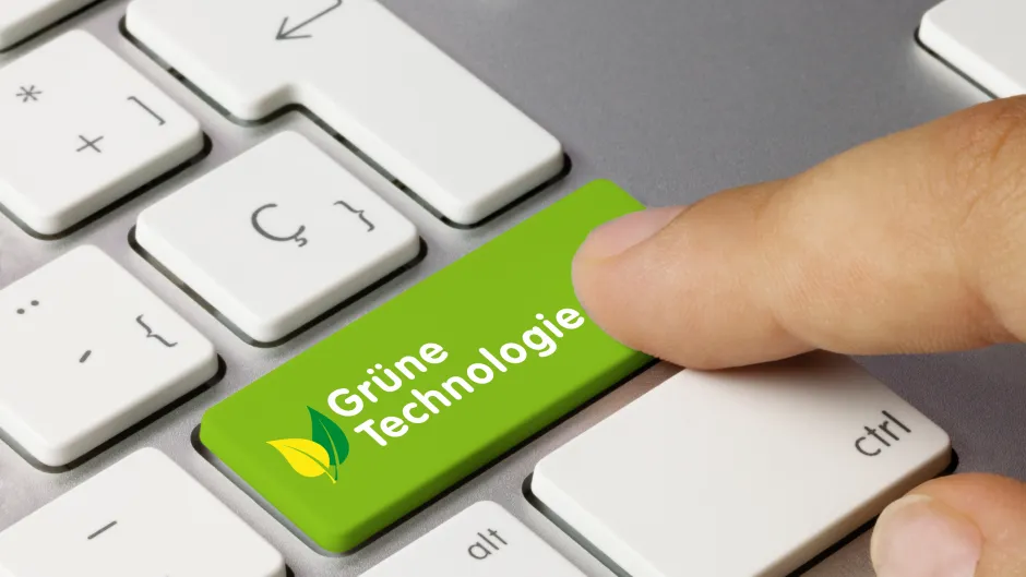 Blick auf eine Somputertastatur - eine Hand drückt eine grün gefärbte Taste mit der Aufschrift "Grüne Technologie"